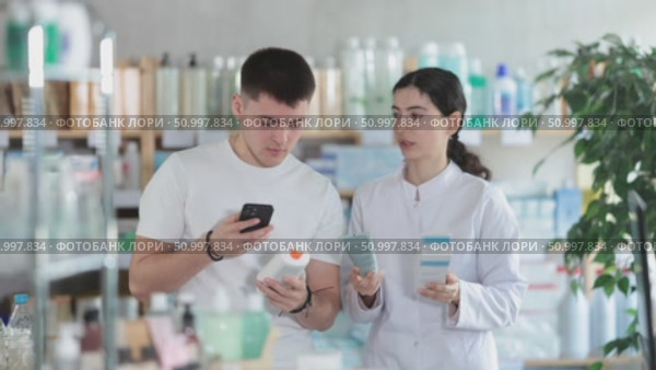 Man scans QR code on box skin cream label. Female pharmacist offers to choose the right gel. Стоковое видео, видеограф Яков Филимонов / Фотобанк Лори