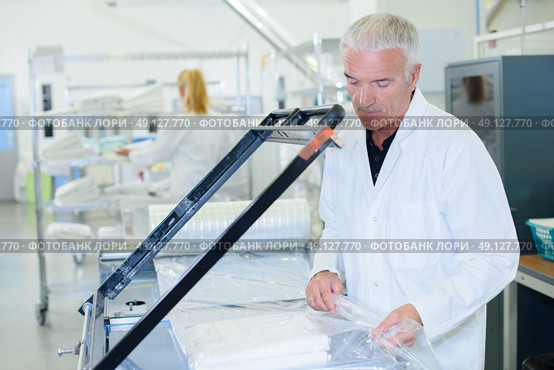 Man shrink wrapping clean laundry. Стоковое фото, агентство Ingram Publishing / Фотобанк Лори