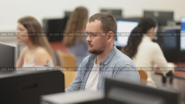 Man student of computer courses looks at monitor screen, types on keyboard and does work. Стоковое видео, видеограф Яков Филимонов / Фотобанк Лори
