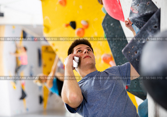 Man talking on mobile phone while exercising at artificial climbing wall. Стоковое фото, фотограф Яков Филимонов / Фотобанк Лори
