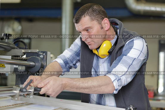 man wearing ear protectors cutting piece of wood. Стоковое фото, агентство Ingram Publishing / Фотобанк Лори