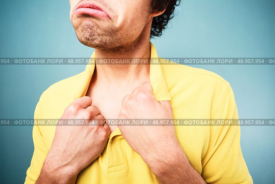 Man with a sad look on his face is pulling at his shirt collar. Стоковое фото, агентство Ingram Publishing / Фотобанк Лори
