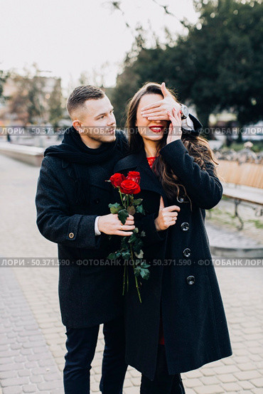 man with roses surprising young girl. Стоковое фото, агентство Ingram Publishing / Фотобанк Лори