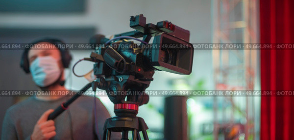 masked cameraman is filming a television show in the studio. TV. Стоковое фото, агентство Ingram Publishing / Фотобанк Лори