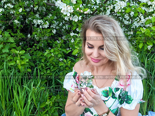 Mature blonde woman enjoys a moment in nature while holding flowers in a lush garden on a sunny day. Стоковое фото, фотограф Кривошеина Елена Леонидовна / Фотобанк Лори