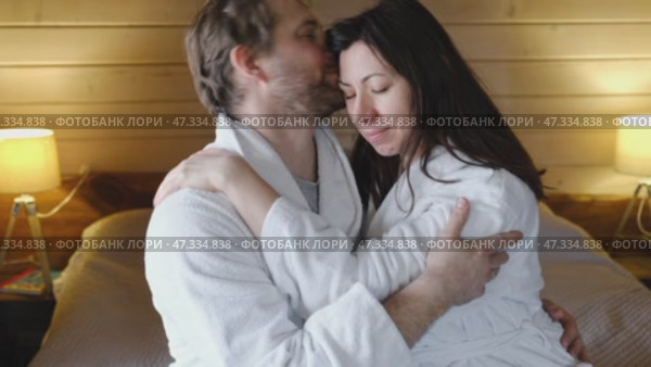 Mature couple in a white bathrobes hugging each other kissing at home bedroom. Intimate Moment. Tender embrace shared between a loving middle age man and woman, husband and wife. Deep love. Vacation. Стоковое видео, видеограф Марина Демидюк / Фотобанк Лори