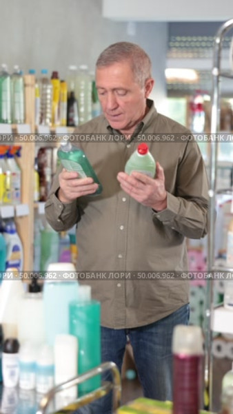 Mature male customer diligently picking out dishwashing liquid. Стоковое видео, видеограф Яков Филимонов / Фотобанк Лори
