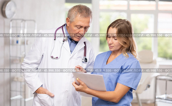 Mature man and middle-aged woman doctors together read new resolution, Стоковое фото, фотограф Яков Филимонов / Фотобанк Лори