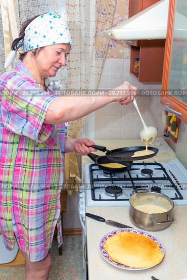 Mature woman bakes pancakes in the kitchen. Стоковое фото, фотограф Акиньшин Владимир / Фотобанк Лори