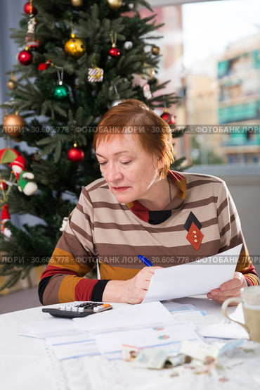 Mature woman calculates utility costs in the new year. Стоковое фото, фотограф Яков Филимонов / Фотобанк Лори