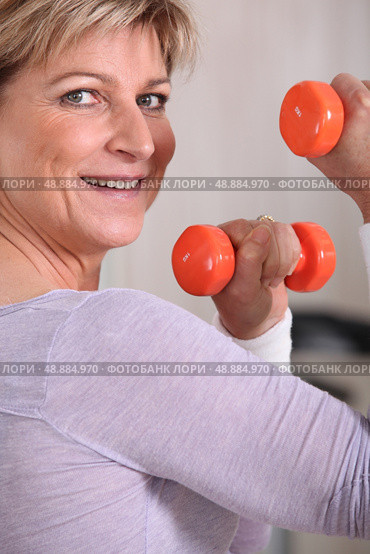 Mature woman using dumbbells. Стоковое фото, агентство Ingram Publishing / Фотобанк Лори