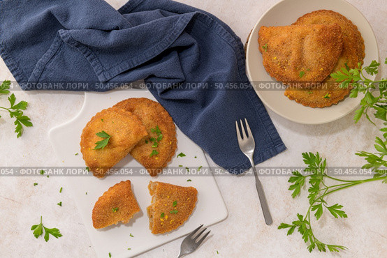 Meat patties and parsley leaves on white ceramic dishes in a kitchen counter top. Стоковое фото, агентство Ingram Publishing / Фотобанк Лори