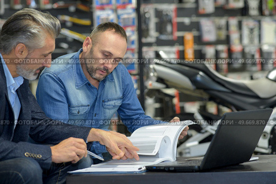 mechanic and smiling customer chatting about motorbike. Стоковое фото, агентство Ingram Publishing / Фотобанк Лори