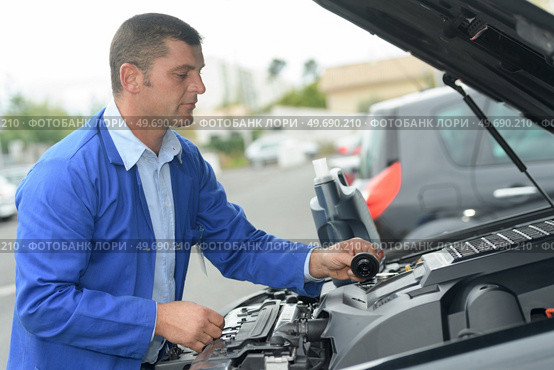 mechanic with scan tool diagnosing car in open hood. Стоковое фото, агентство Ingram Publishing / Фотобанк Лори