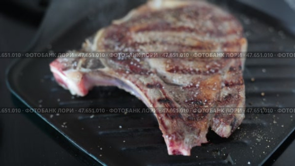 Medium rare fried entrecote beef steak in cast iron pan with salt and pepper. Стоковое видео, видеограф Яков Филимонов / Фотобанк Лори