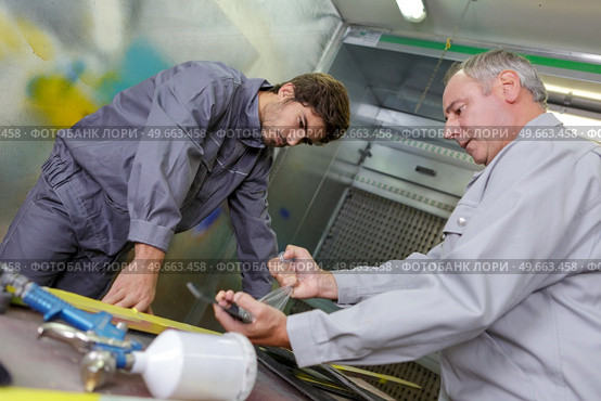 Men in paint spraying area. Стоковое фото, агентство Ingram Publishing / Фотобанк Лори