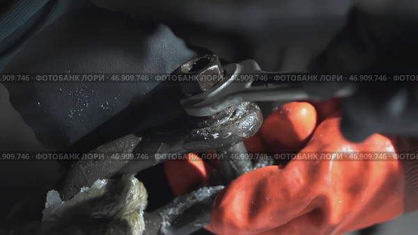 Men's hands in orange gloves on board the ship tighten the screw from the ship's anchorage at night. Стоковое фото, фотограф David Kashakhi / Фотобанк Лори