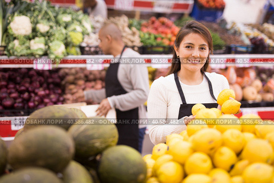Merchandiser lays out ripe lemons on the shelves in supermarket. Стоковое фото, фотограф Яков Филимонов / Фотобанк Лори