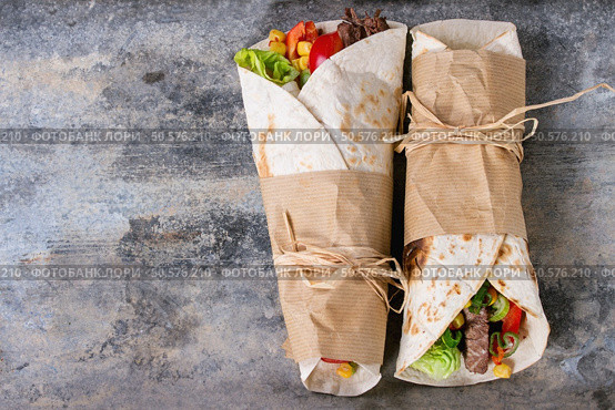 Mexican style dinner. Two papered tortillas with beef and vegetables served with nachos chips and guacomole sauce over old wooden background. Flat lay. Tortillas and nachos. Стоковое фото, агентство Ingram Publishing / Фотобанк Лори