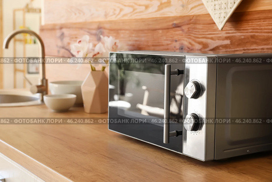 Microwave oven on wooden tabletop in kitchen. Стоковое фото, фотограф Pixel_shot / Фотобанк Лори