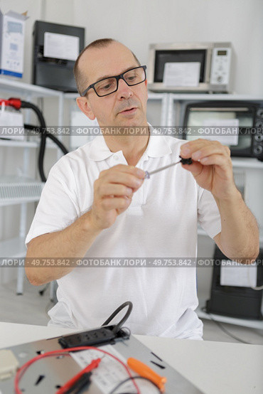 middle age technician fixing device. Стоковое фото, агентство Ingram Publishing / Фотобанк Лори