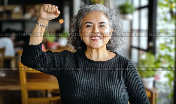 Middle aged hispanic woman with raised fist of empowerment, strength and women solidarity, International Womens Day concept. Стоковое AI-изображение, AI-художник Анастасия Золотницкая / Фотобанк Лори