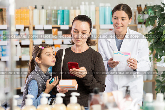 Middle-aged woman with daughter scanning barcode on pills in drugstore. Стоковое фото, фотограф Яков Филимонов / Фотобанк Лори