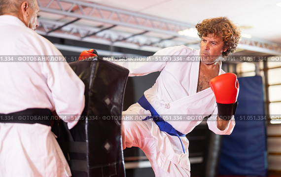 Middle‑aged man practicing kick on shield in karate dojo. Стоковое фото, фотограф Яков Филимонов / Фотобанк Лори