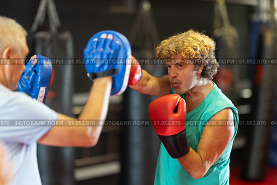 Middle‑aged man practicing punches on mitts with partner. Стоковое фото, фотограф Яков Филимонов / Фотобанк Лори