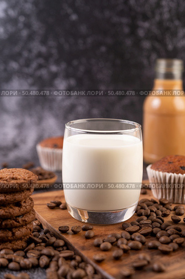 Milk in a glass, complete with coffee beans, cupcakes, bananas and cookies on a wooden plate. Стоковое фото, агентство Ingram Publishing / Фотобанк Лори