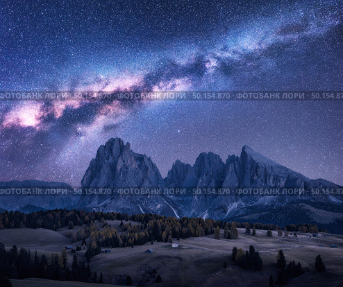 Milky Way over beautiful mauntains at night. Autumn landscape with mountains, purple sky with stars and bright milky way, buildings, trees, high rocks. Alpe di Siusi in Dolomites, Italy. Space. Стоковое фото, агентство Ingram Publishing / Фотобанк Лори