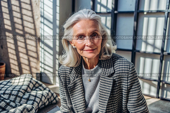 Minimalism. A studio portrait of a stylish, elegant elderly woman, a pensioner of 70 years old, in an interior and clothes of calm tones. The concept of the elderly. Стоковое AI-изображение, AI-художник Photojuli / Фотобанк Лори
