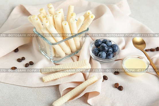 Миски с вкусными вафельными трубочками, черникой и сгущенным молоком на белом гранж-фоне. Стоковое фото, фотограф Pixel_shot / Фотобанк Лори