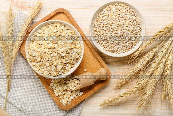 Миски сырой овсянки, перловой крупы и колосков на деревянном фоне. Стоковое фото, фотограф Pixel_shot / Фотобанк Лори