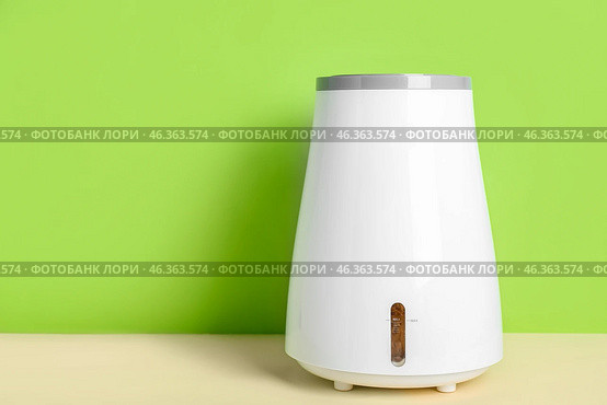 Modern humidifier on table near green wall. Стоковое фото, фотограф Pixel_shot / Фотобанк Лори