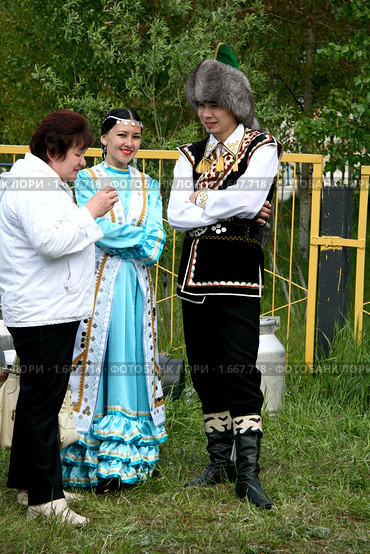 Молодая пара в национальных костюмах угощает кумысом женщину (2008 год). Редакционное фото, фотограф Владимир Мельников / Фотобанк Лори