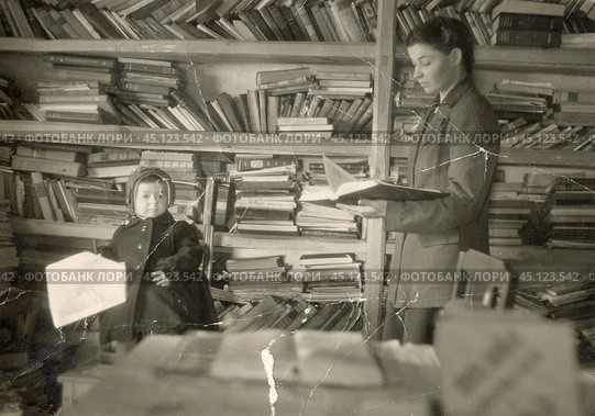 Молодая женщина с маленьким ребенком на фоне стеллажей с книгами. 1940-е годы. Стоковое фото, фотограф Retro / Фотобанк Лори