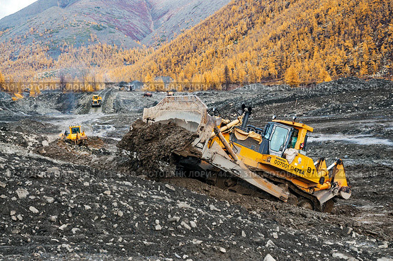 Мощный Японский бульдозер Komatsu d475 в горной местности, снимает верхний слой грунта. Золотодобывающая промышленность Якутии ( Оймяконский район ) (2009 год). Редакционное фото, фотограф Павел Просянов / Фотобанк Лори