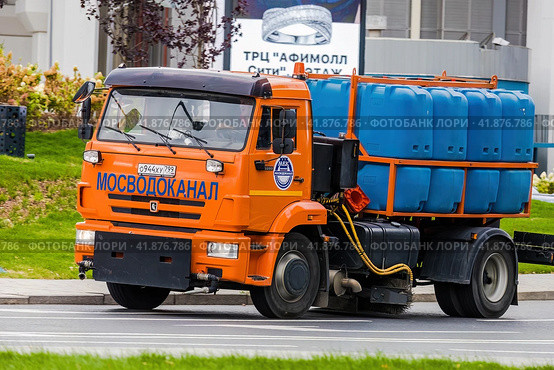 Moscow municipal service truck drive on city streets. Orange KAMAZ watering and sweeping truck in motion. Редакционное фото, фотограф Константин Григорьев / Фотобанк Лори