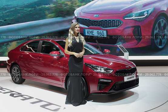 Московский автосалон 2018 года, девушка модель у красного автомобиля KIA церато. Редакционное фото, фотограф Дмитрий Неумоин / Фотобанк Лори