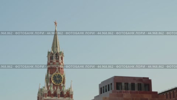 Москва, Красная площадь. Спасская башня с курантами. Три часа дня на циферблате часов. Фрагмент стены мавзолея Ленина. Голубое безоблачное небо. Редакционное видео, видеограф Сергей Никифоров-Гордеев / Фотобанк Лори