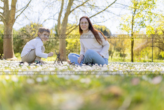 Mother and son building small teepee with branches in blooming meadow. Стоковое фото, фотограф Константин Шишкин / Фотобанк Лори