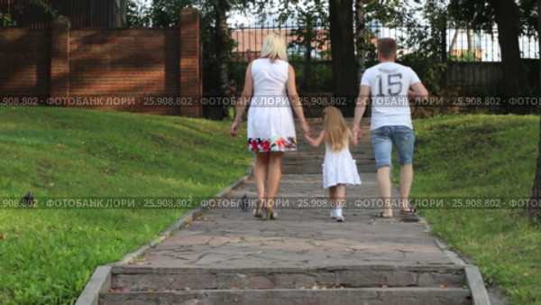 Mother, father, little daughter walk in summer park, back view. Стоковое видео, видеограф Светлана Додух / Фотобанк Лори