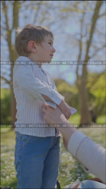 Mother helping child buttoning shirt in park. Стоковое видео, видеограф Константин Шишкин / Фотобанк Лори