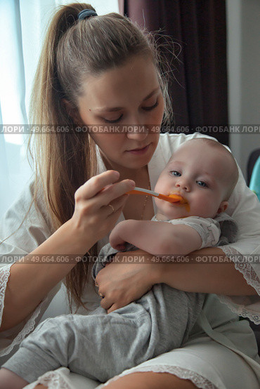 Mother Lovingly Feeding Her Baby Some Food, Precious Moment Unfolds. Стоковое фото, фотограф Aleksandr Golubev / Фотобанк Лори