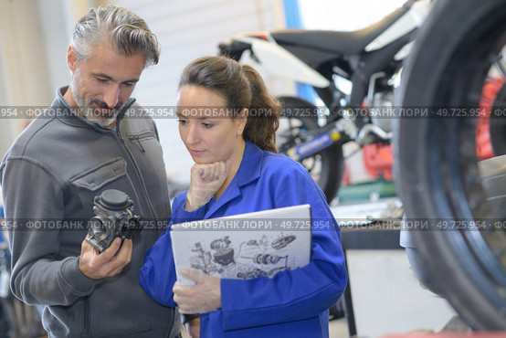motorcycle mechanics looking at carburetor. Стоковое фото, агентство Ingram Publishing / Фотобанк Лори