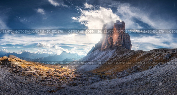 Mountain pass and blue sky with clouds at sunset in autumn. Beautiful panoramic landscape with rocks, alp mountains, stones, path, house, grass on hills. Tre Cime, Dolomites, Italy. Colorful scenery. Стоковое фото, агентство Ingram Publishing / Фотобанк Лори