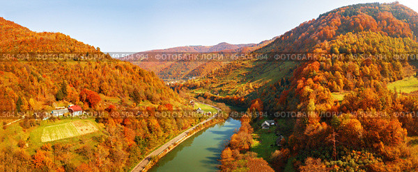 Mountain river flows in autumn colored valley. Panorama of road and village in river canyon. Sunny fall day in Carpathian mountains on border with Poland and Slovakia, Ukraine. Стоковое фото, агентство Ingram Publishing / Фотобанк Лори
