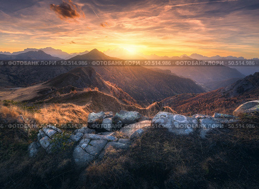 Mountain valley at colorful sunset in autumn in Dolomites, Italy. Colorful landscape with rocks, stones, mountain ridges, hills, orange grass and forest, golden sky with clouds in fall. Hiking. Nature. Стоковое фото, агентство Ingram Publishing / Фотобанк Лори