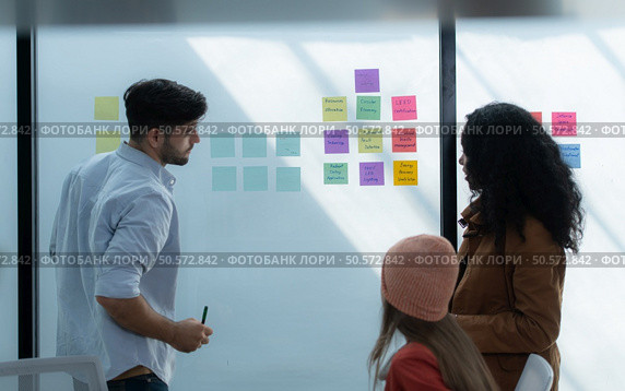 Multiethnic startup business team on meeting in modern bright office interior brainstorming, working on laptop and tablet computer. Стоковое фото, агентство Ingram Publishing / Фотобанк Лори